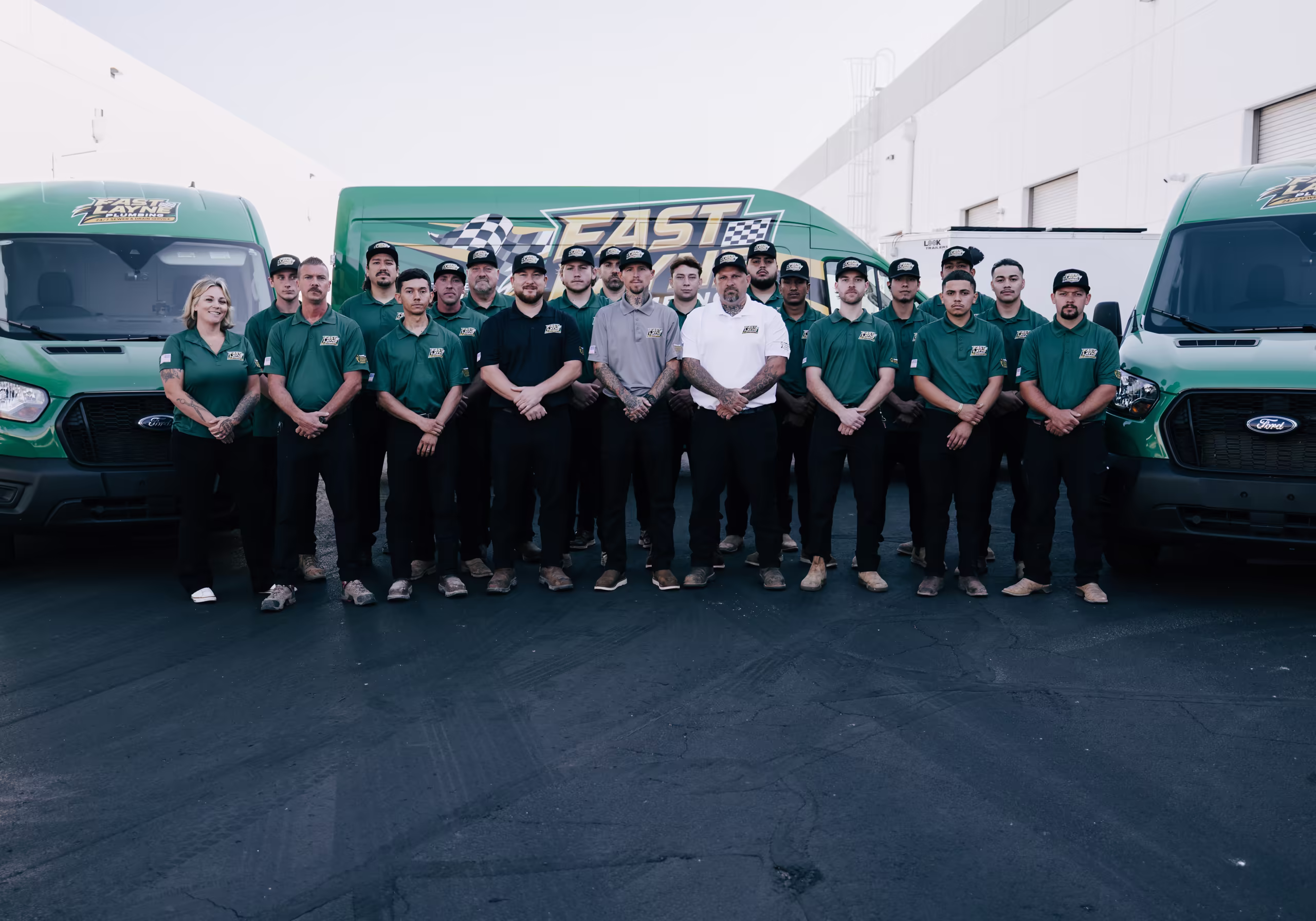 Fast Layne Plumbing team in green uniforms standing in front of company vans