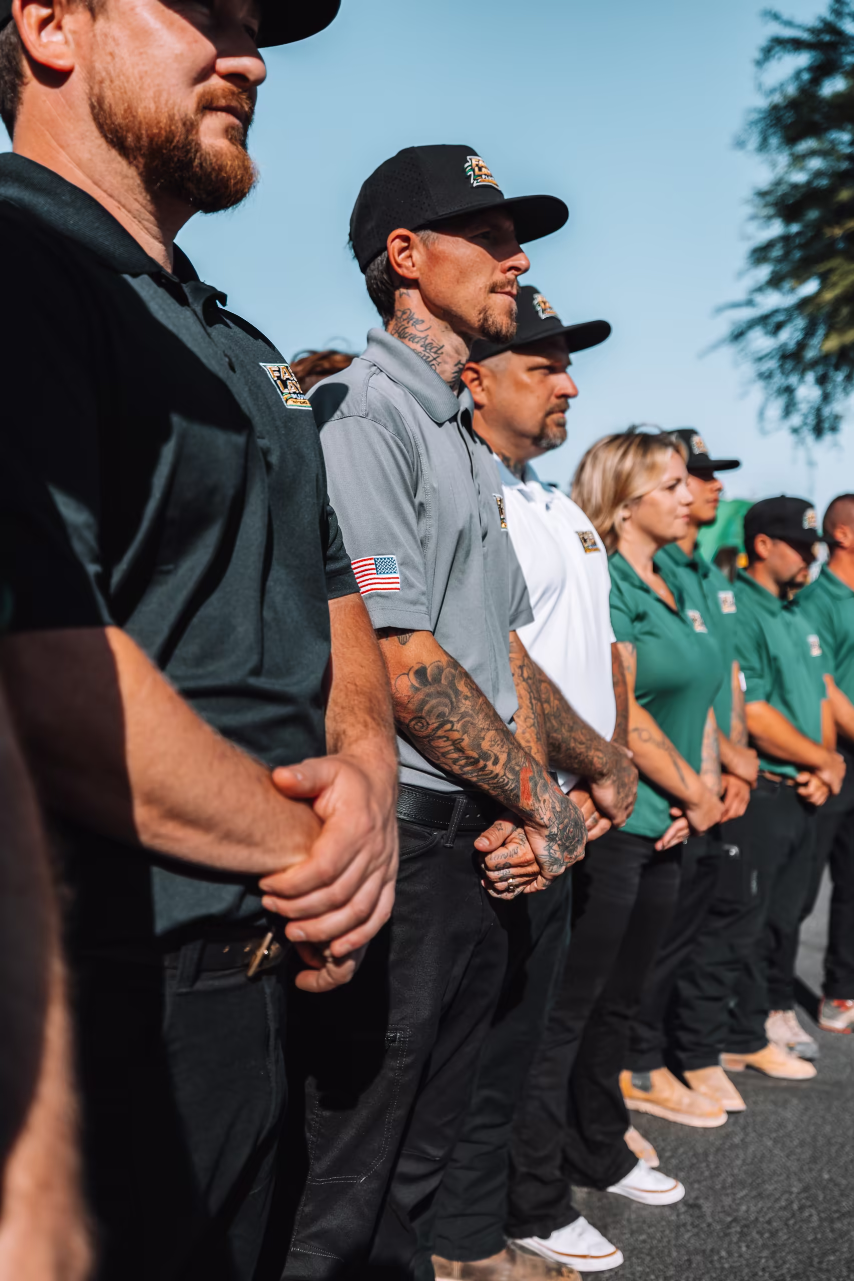 Fast Layne Plumbing technicians in uniform polos and caps standing in a line outdoors